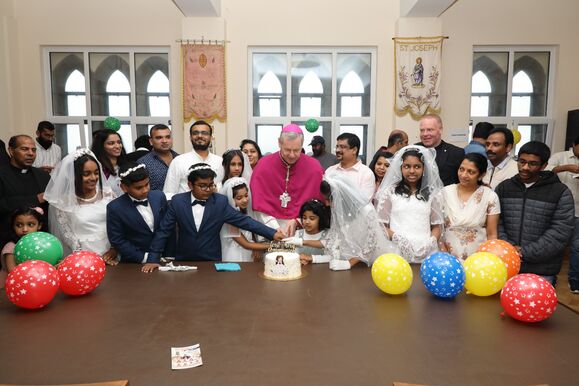 Bishop Fintan cuts the cake with the First Holy Communion Children