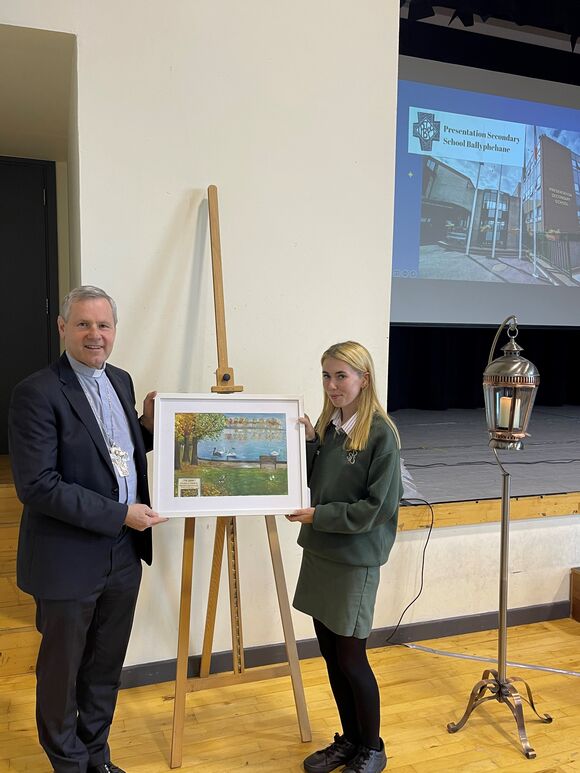 A student council member presents Bishop Fintan with a painting of ”The Lough” created by art teacher Ms. Wall. 
